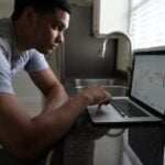 man in gray t-shirt using macbook pro