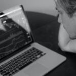 grayscale photo of man looking at macbook pro