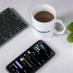 a cell phone sitting next to a cup of coffee