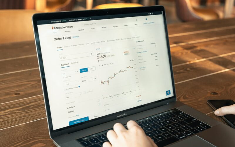 person using macbook pro on brown wooden table
